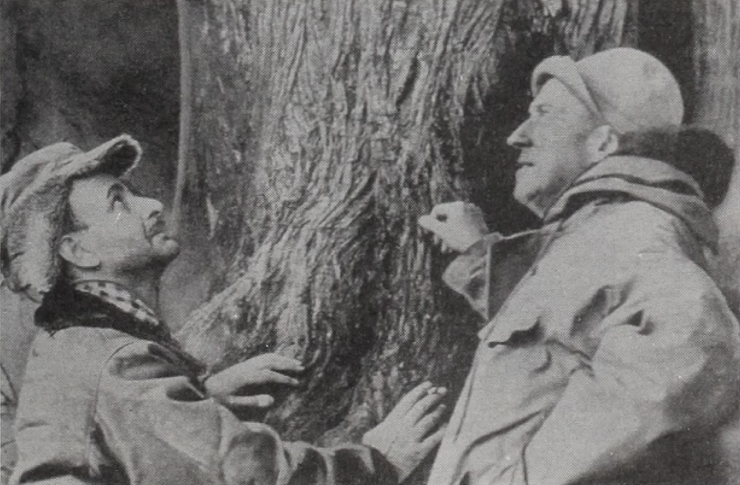 Blac-and-white photograph of two botanists beside tree trunk