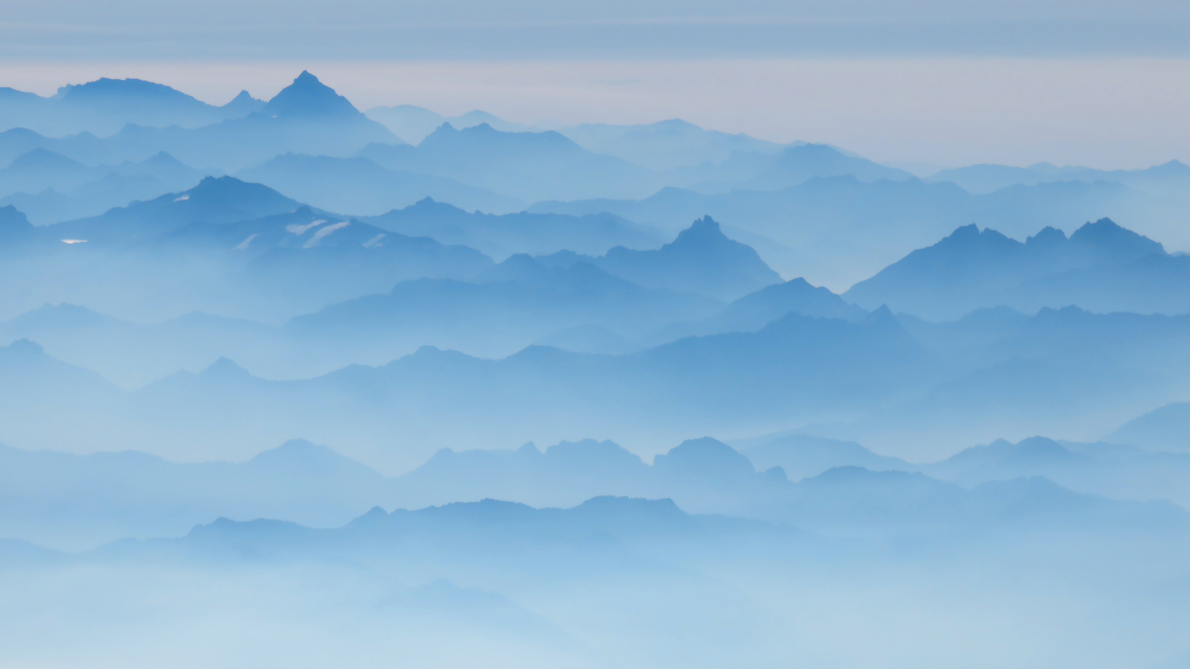 Mountain ranges shrouded with smoke and cast in blue light