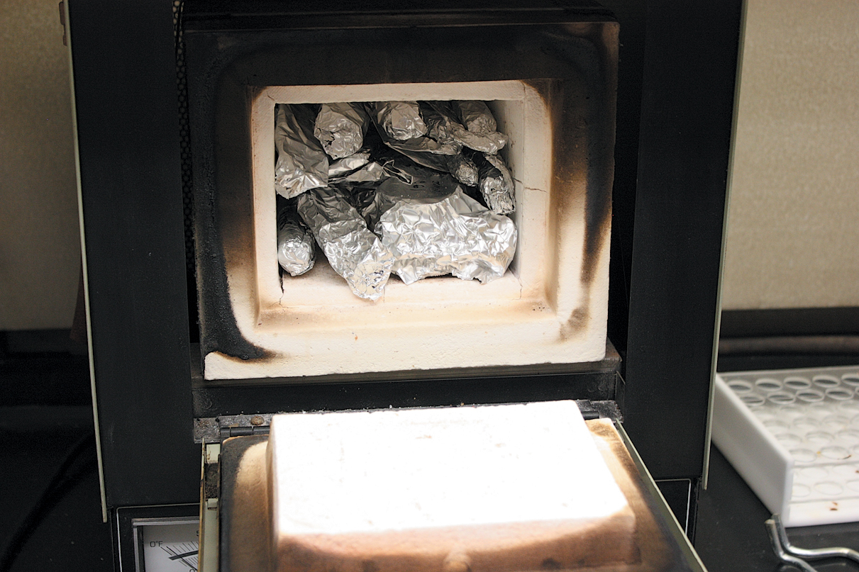 A color photo of foil-wrapped wood samples in a furnace.
