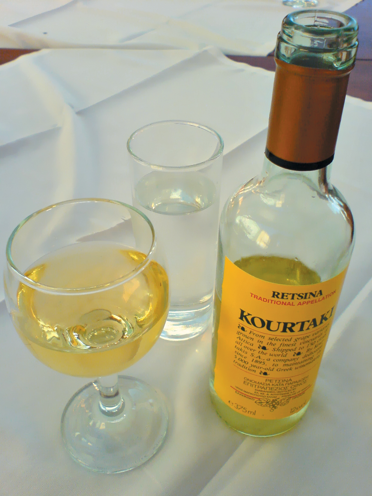 A color photo of a bottle of Retsina and a glass of the same.