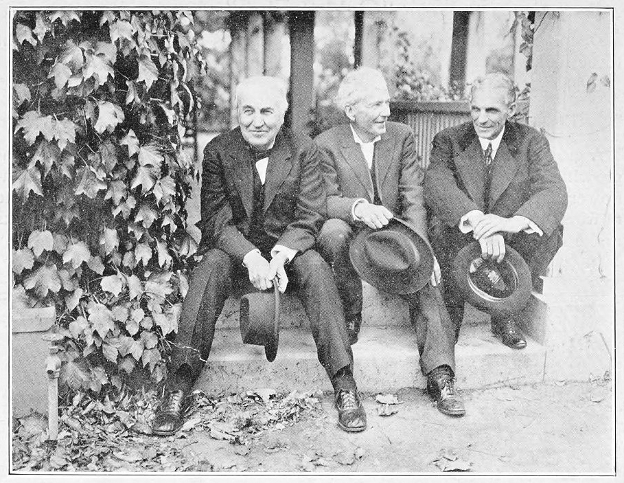 A black and white photo of three men sitting on a stone step.