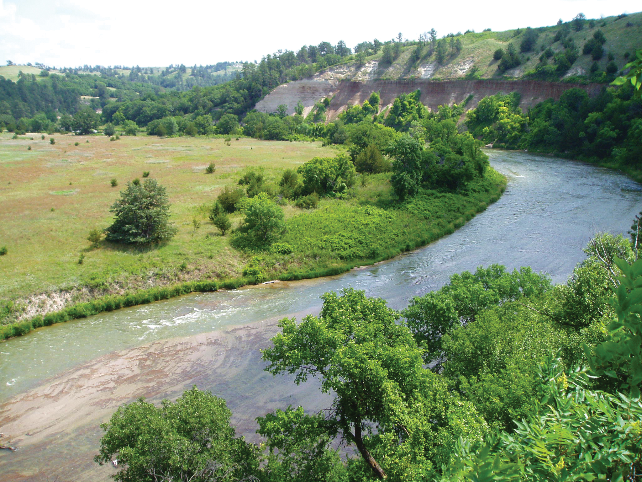 View of snaking river with green trees on steep bank