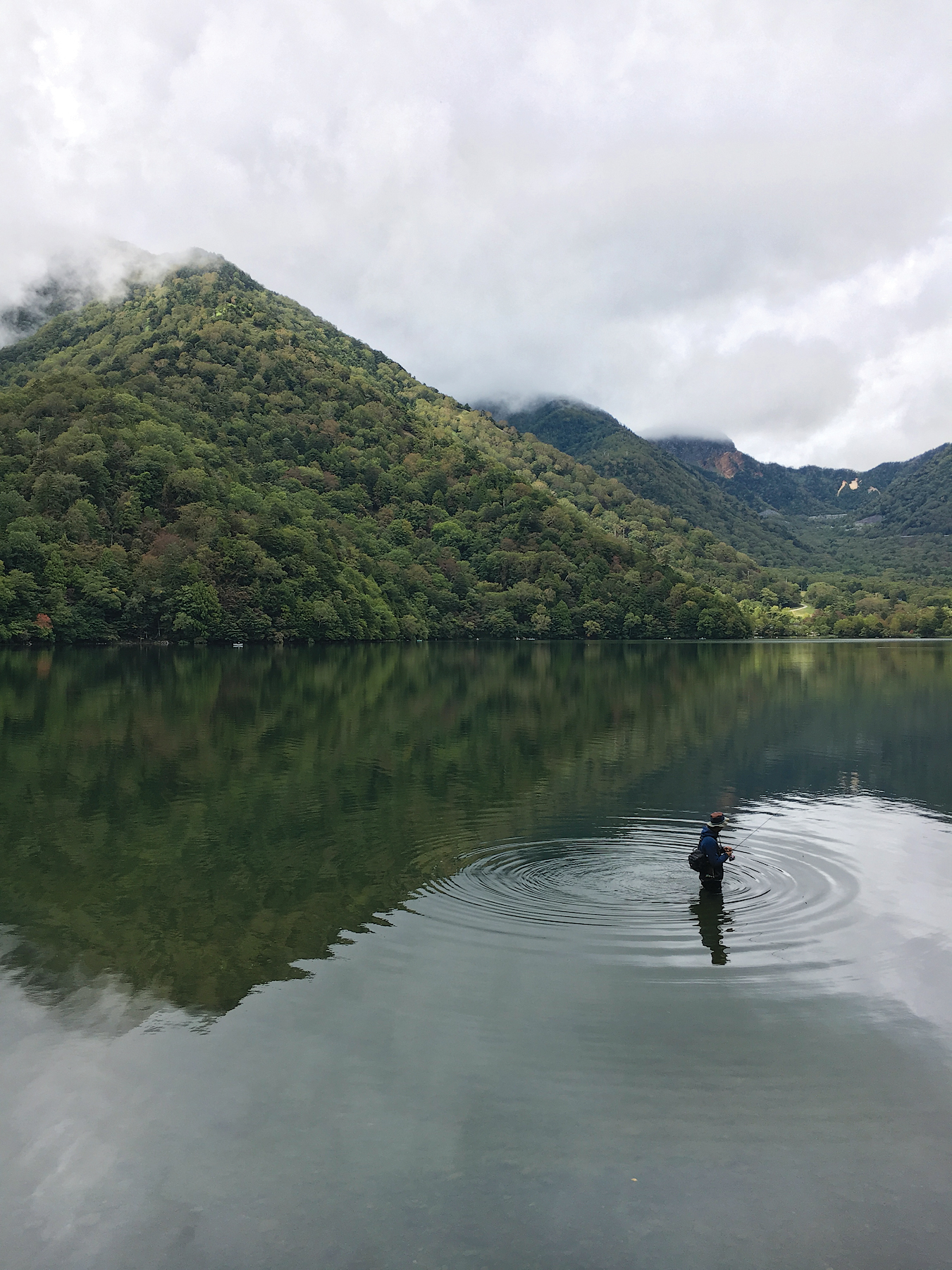 View of foggy lake with mountains on far side