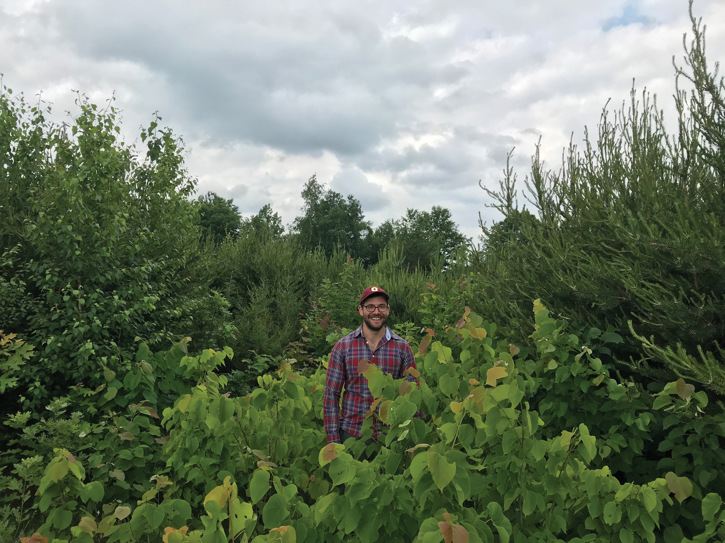 Photo of Jake Grossman standing in grove of young trees