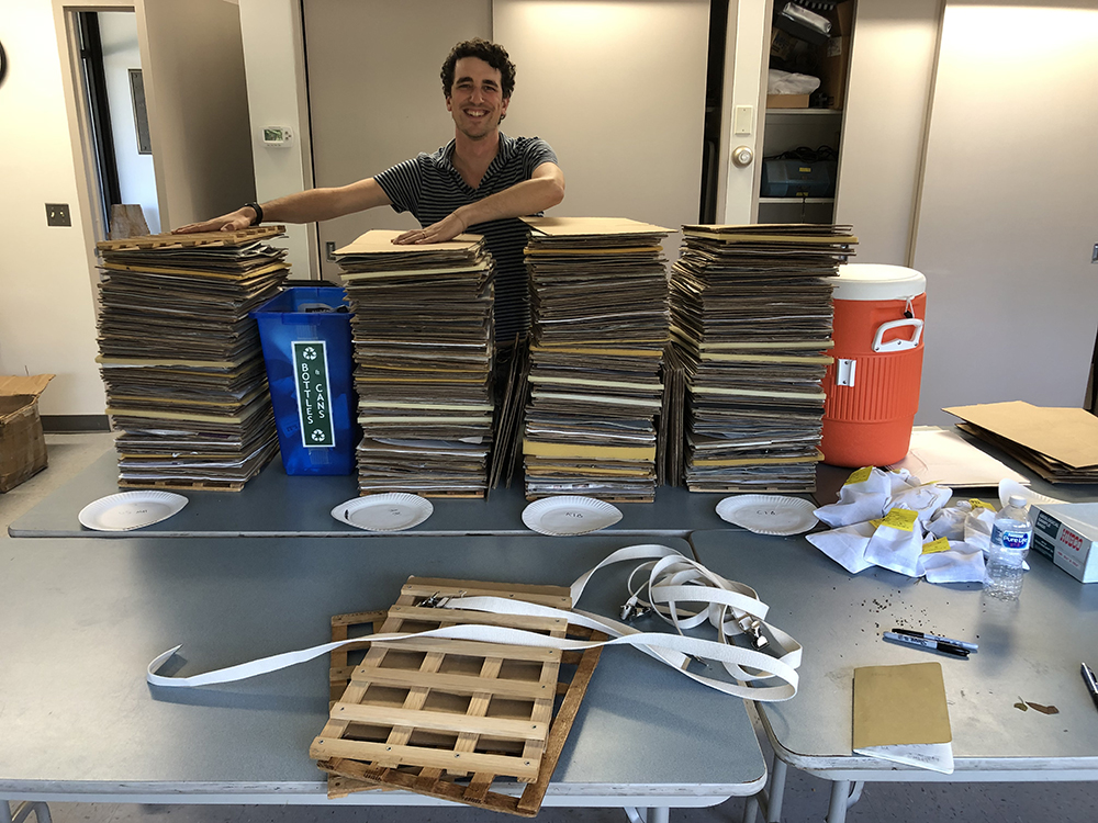 Jared Rubinstein poses alongside the 400 herbarium vouchers collected during the expedition. Photo by Andrew Gapinski.