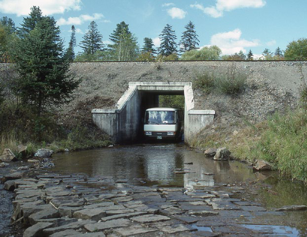 Photo of van driving through narrow underpass with standing water on road
