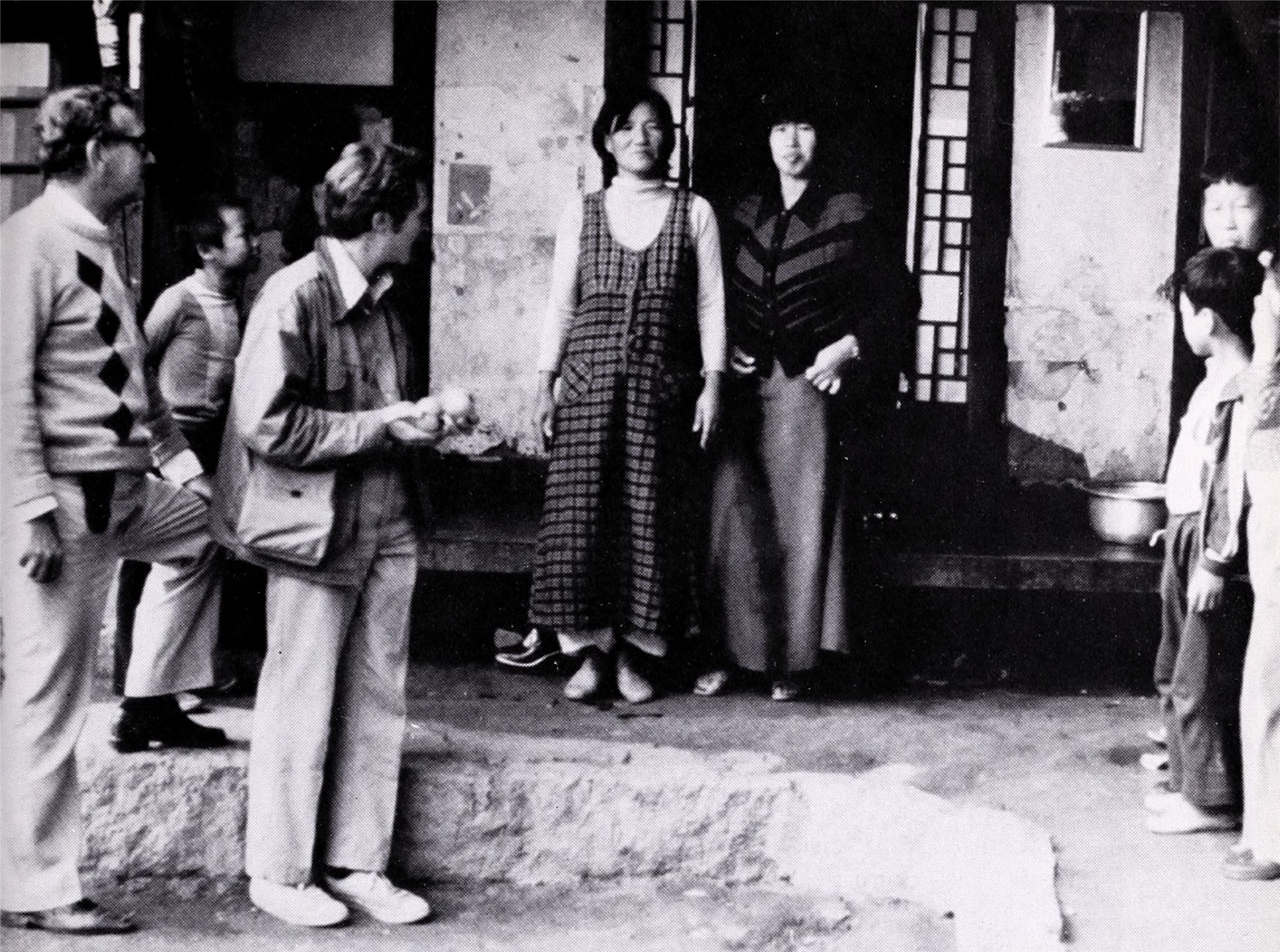 Black-and-white photograph showing people gathered near porch of house