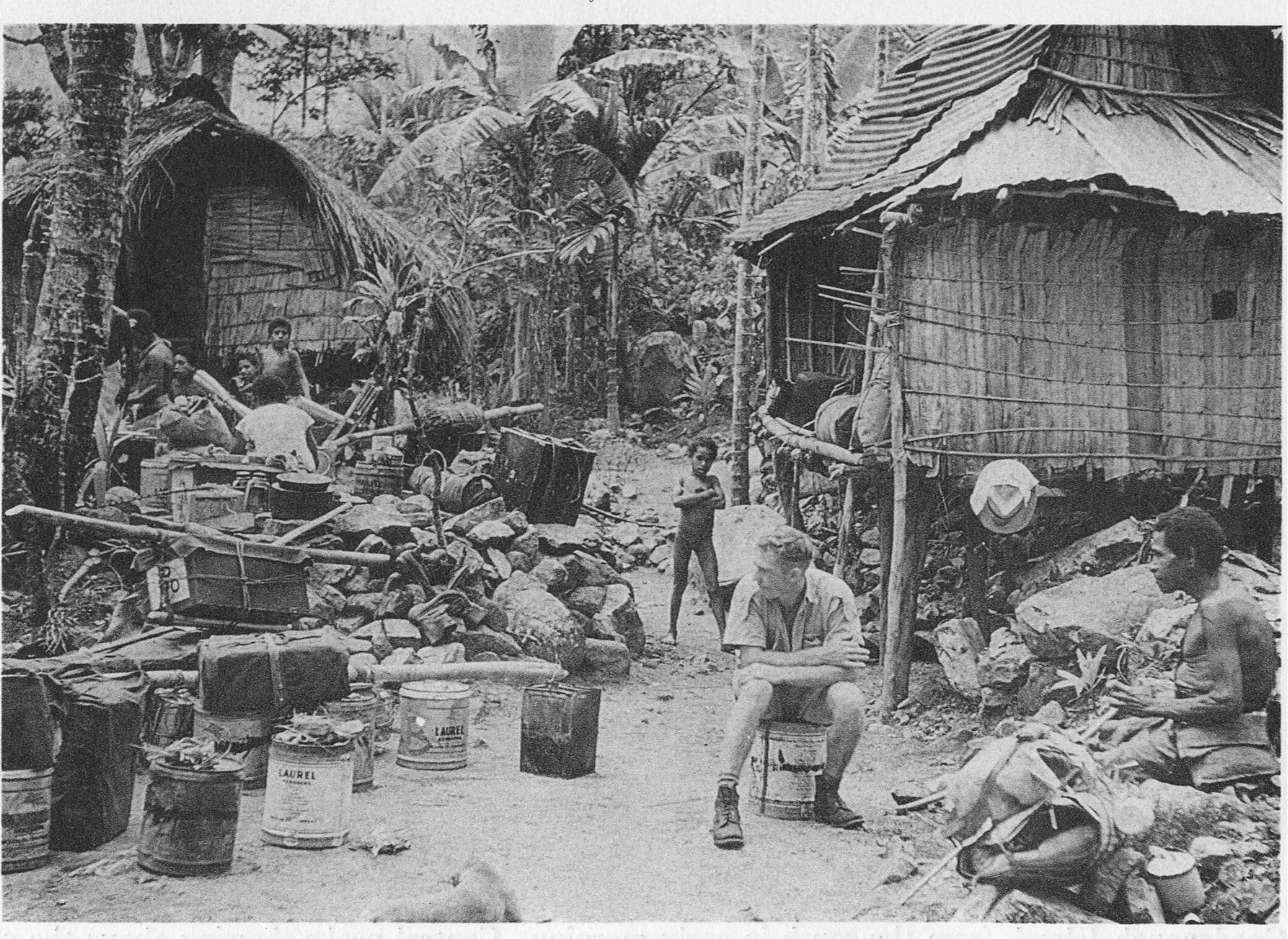 The expedition transport pauses in Garuwata village at 2100 feet (640 meters), on the east slopes of Goodenough Island. Kenneth Wynn may be seen seated in foreground.