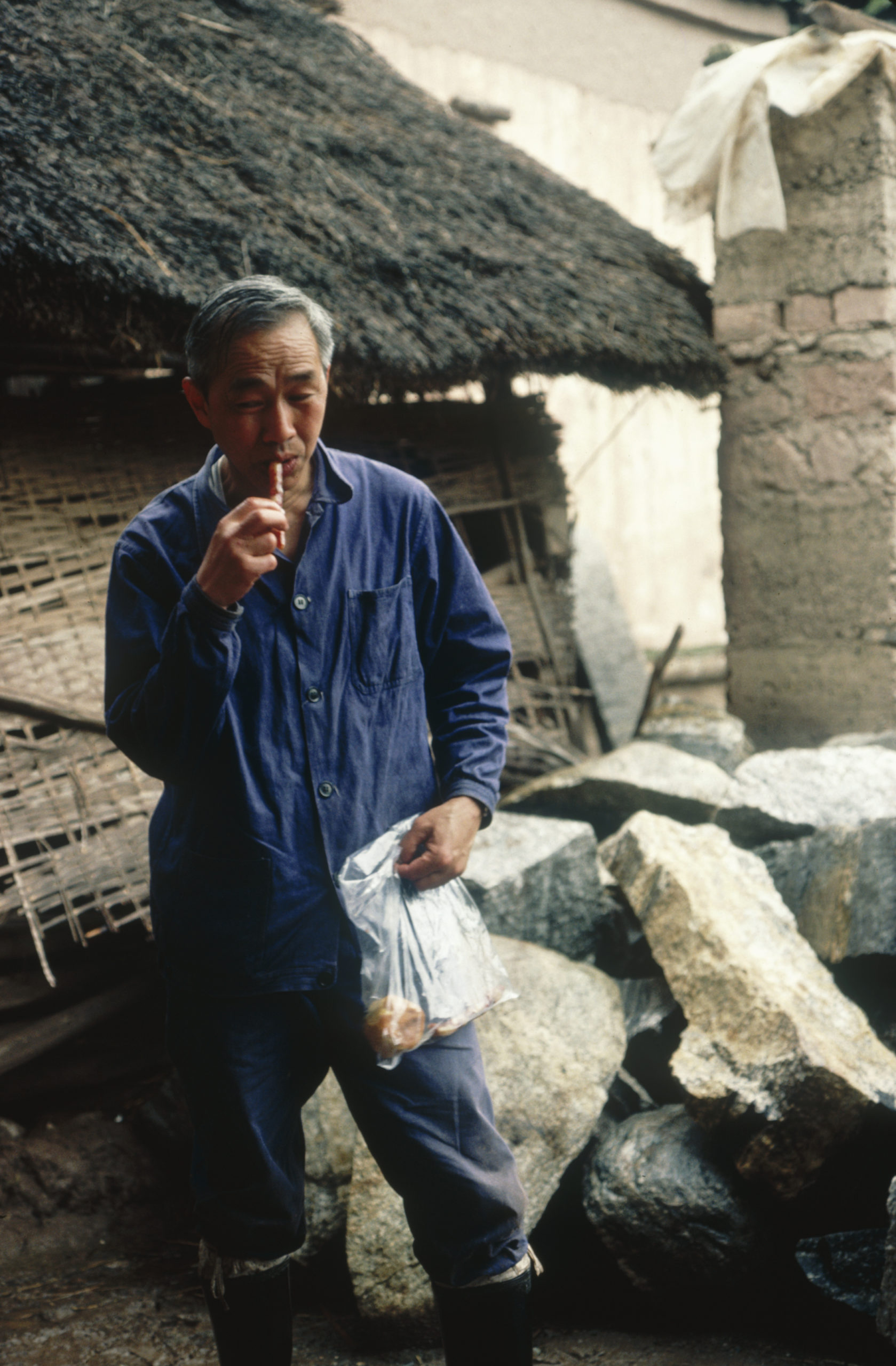 1984 SABE team member Li Xi-wen eating Chinese sausage on his arrival at Yangbi, Yunnan.