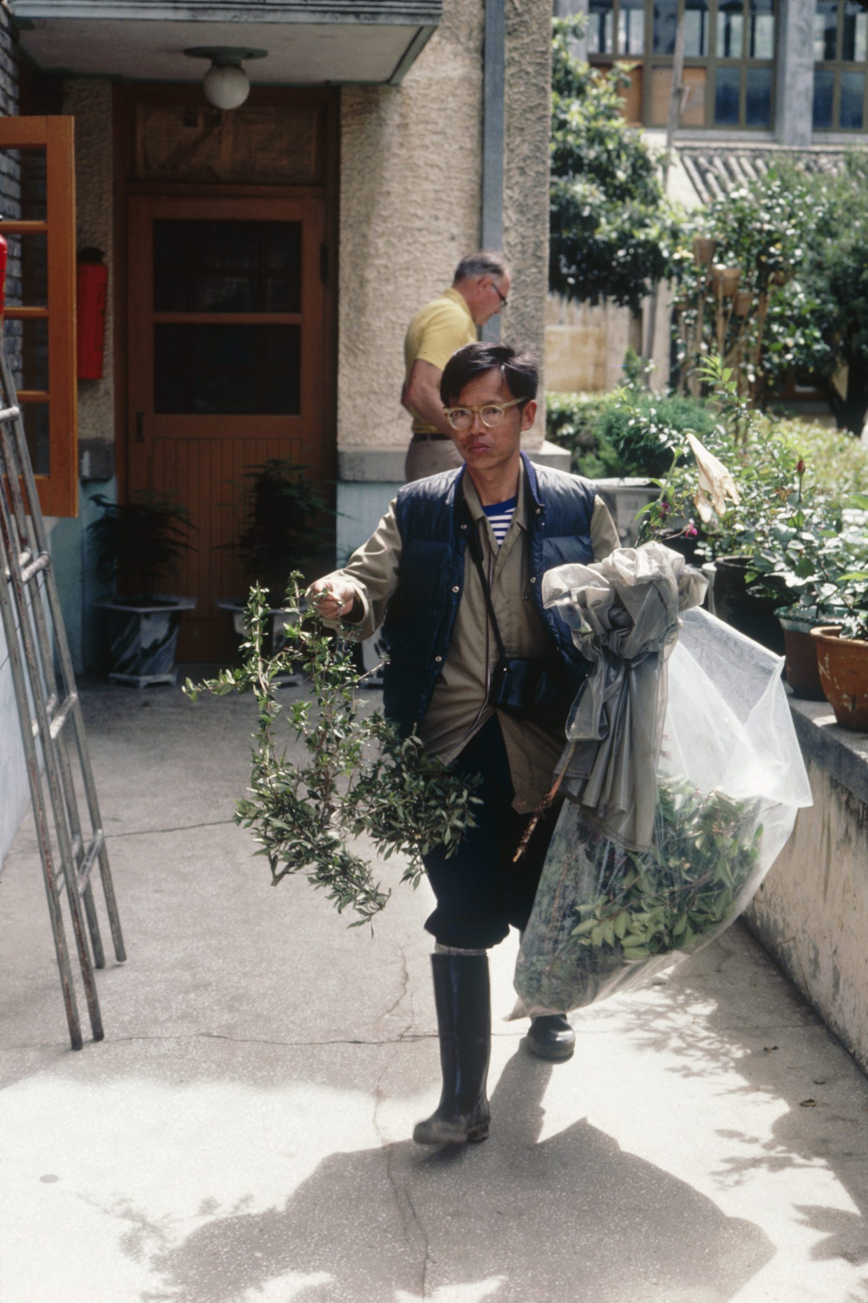 1984 SABE team member Yu Shawen with bag of specimens and Dan Nicolson (background) returning to Xiaguan, Yunnan.