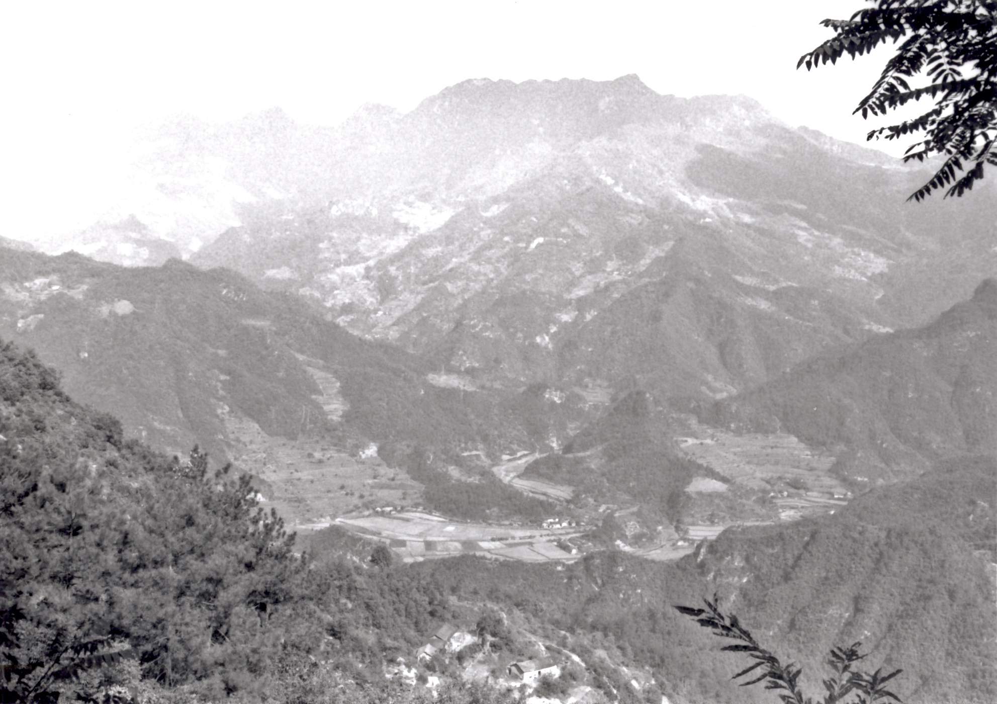 A view from an elevated location across a valley to a mist-shrouded mountain peak in the background.