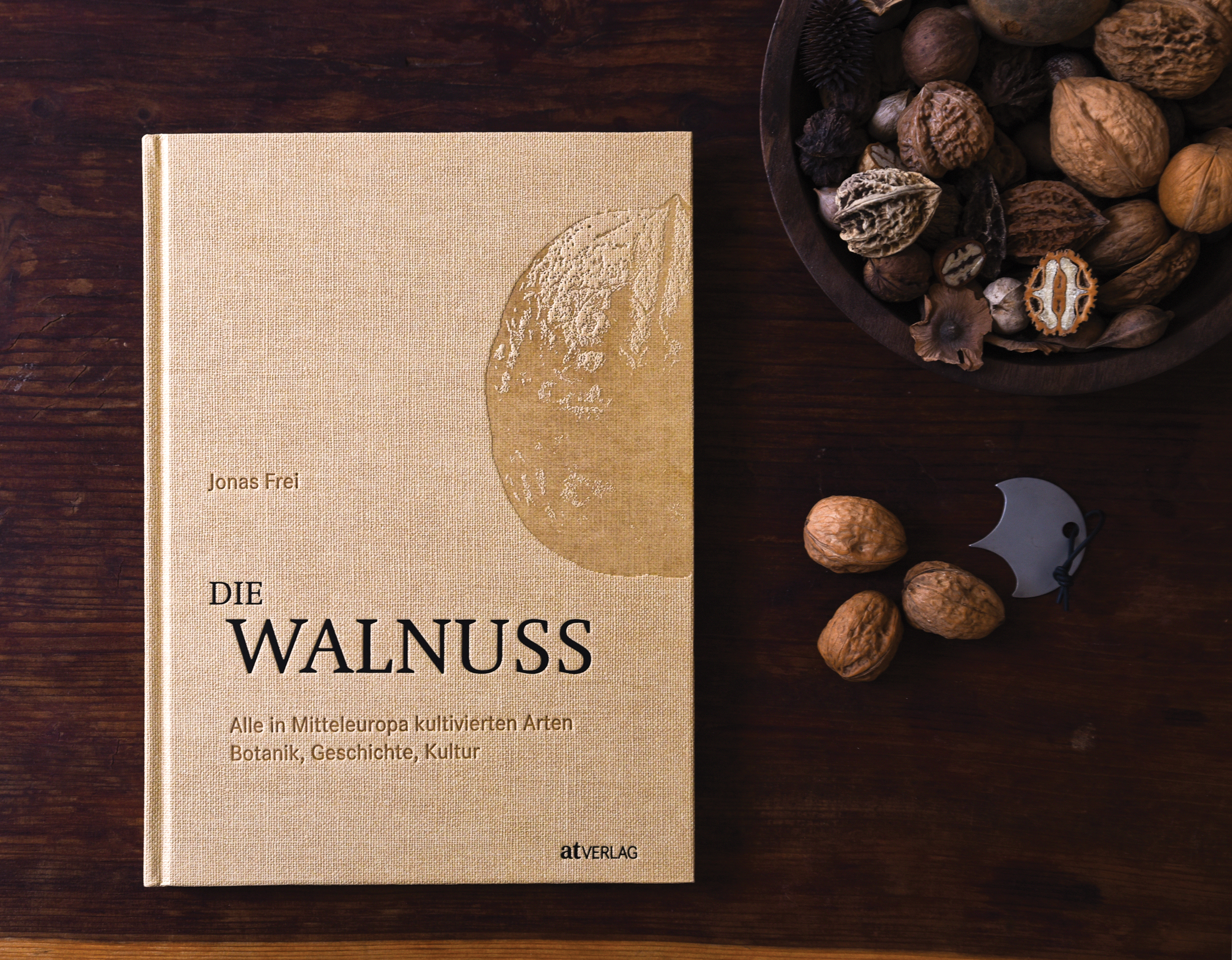 Photograph of book sitting beside bowl of walnut family fruits