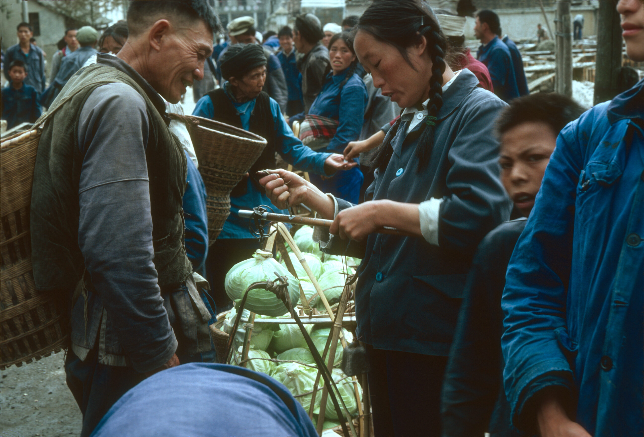 A woman weighs a cabbage in the market in Lichuan.
