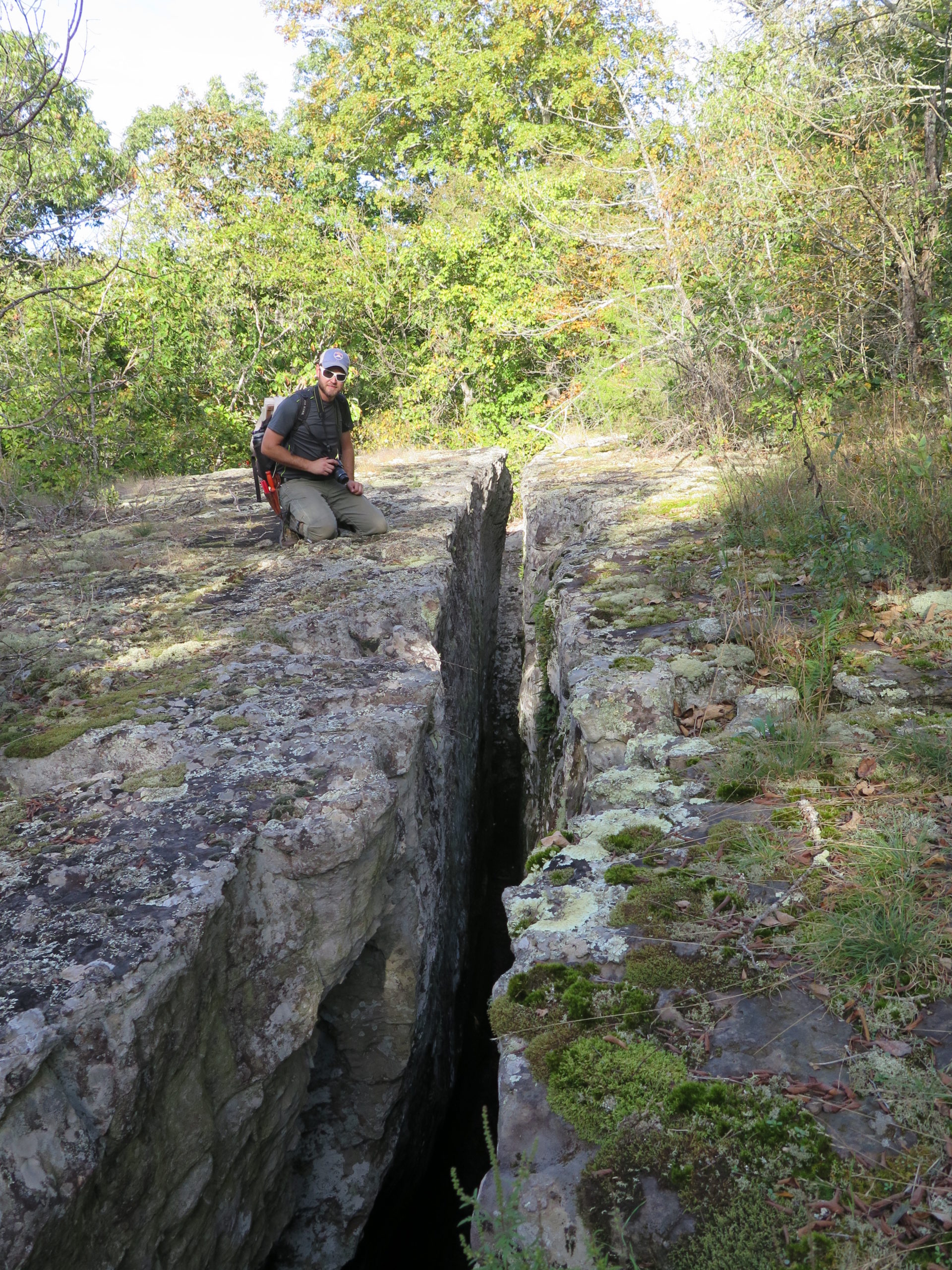 Ian Jochems kneels beside a crevasse in the limestone rocks of the Kings River Falls Natural Area. These fissures can be as much as 40 feet (12 meters) deep.