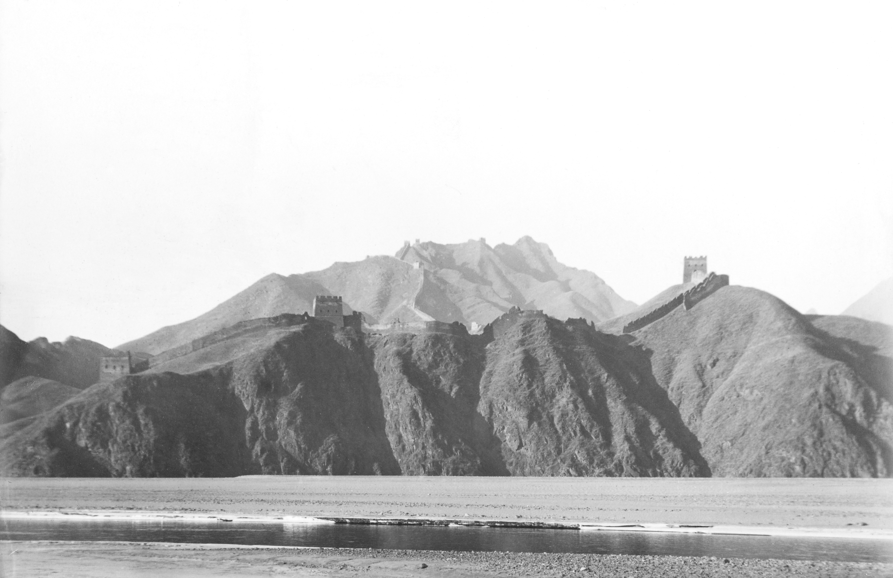 Black-and-white photograph of Great Wall of China on mountains overlooking river