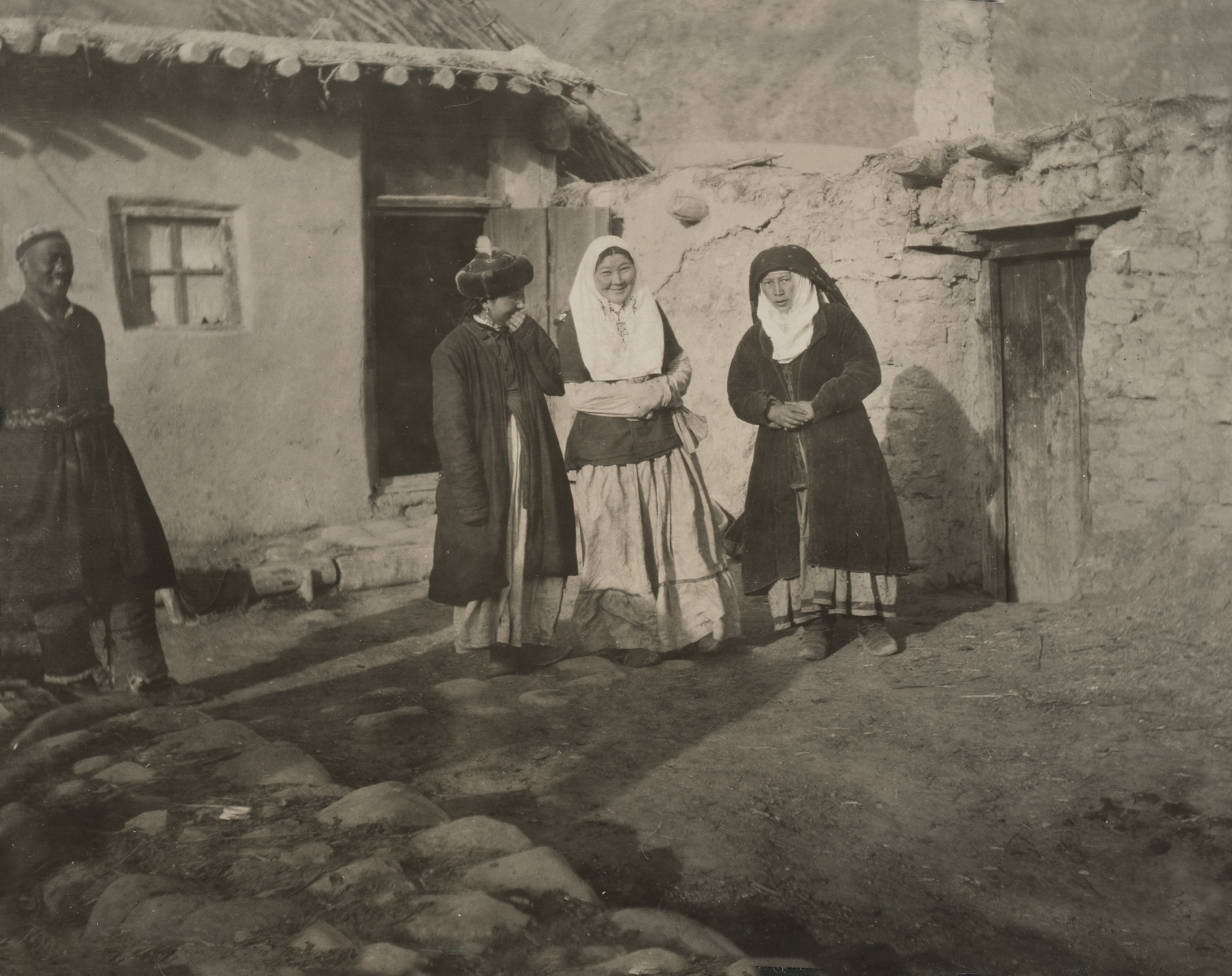 A three women and a man stand before the dwelling in which Meyer stayed in Tchoa in the Tekes Valley, Xinjiang in 1911.
