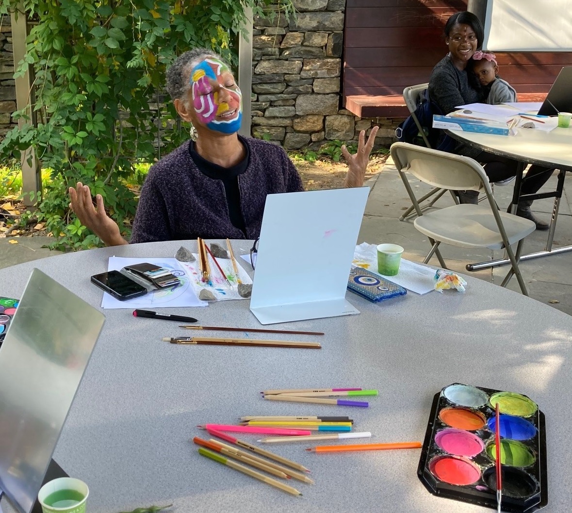 Woman with painted face and art supplies at table