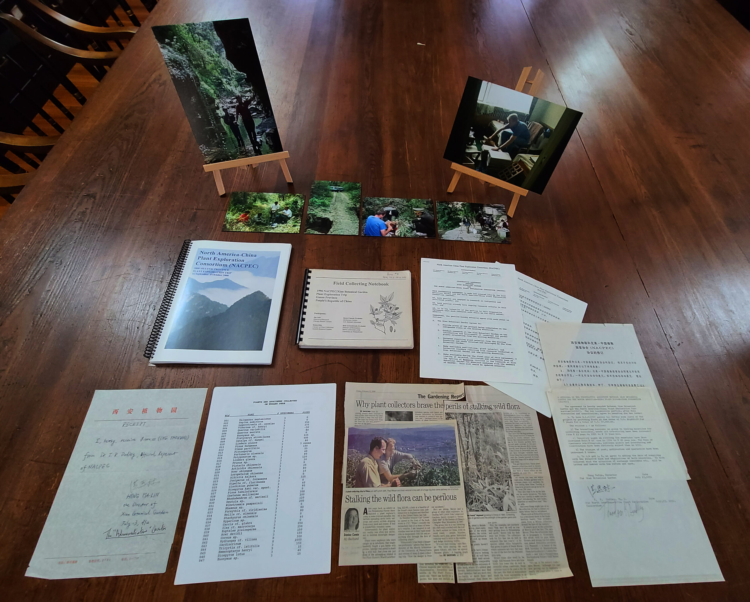 Photographs, reports, and documents from the NACPC Archives arranged on a wooden table.