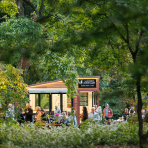 Several people mill about amongst the trees and a Mobile Visitor Center